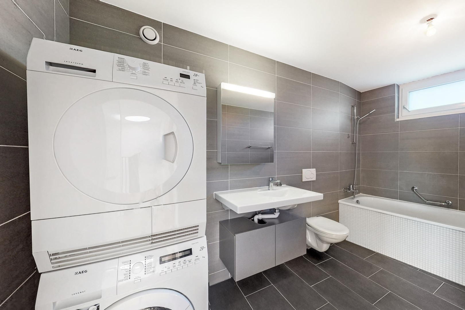 Badezimmer mit Waschtisch, Wanne und Trockner