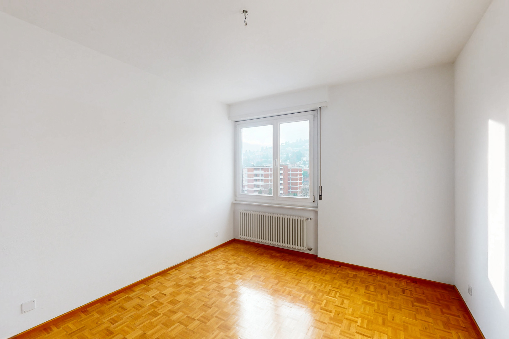 Leerer heller Raum mit Parkett und Fenster