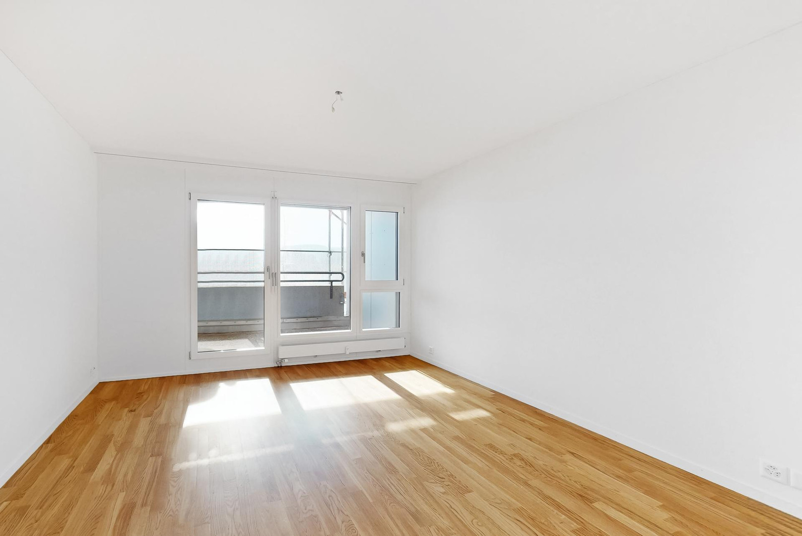 Helles, leeres Wohn-/Schlafzimmer mit Balkonzugang