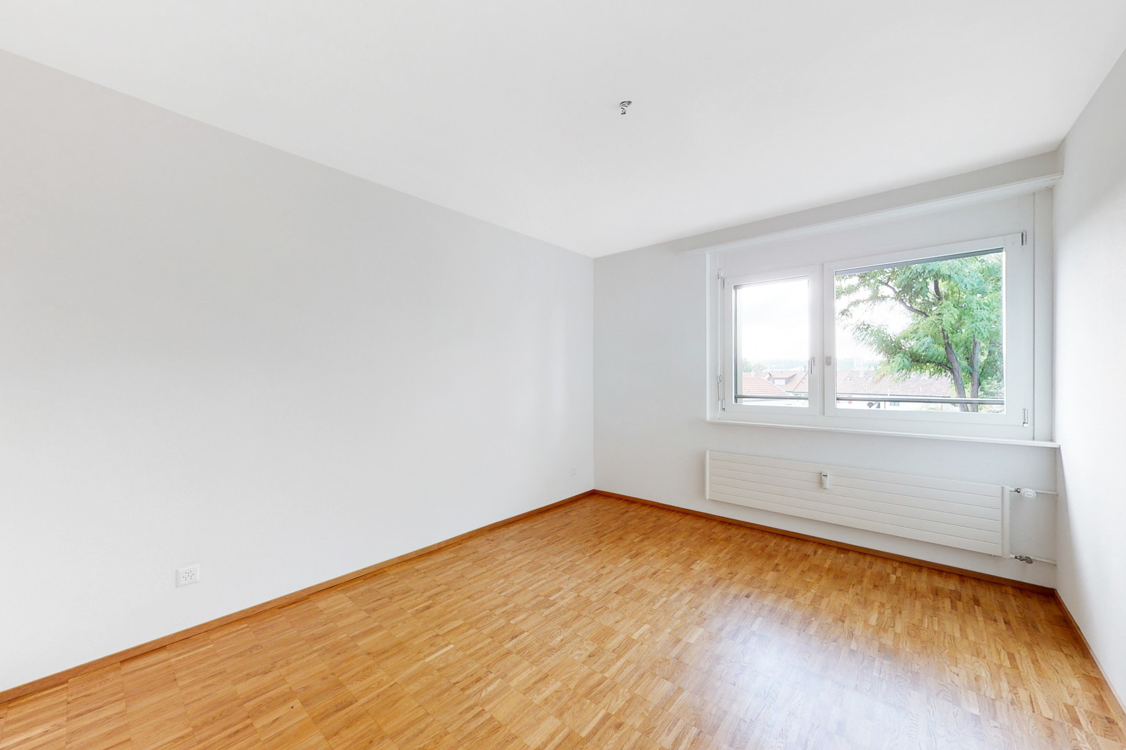 Heller leerer Raum mit Parkett und Fenster