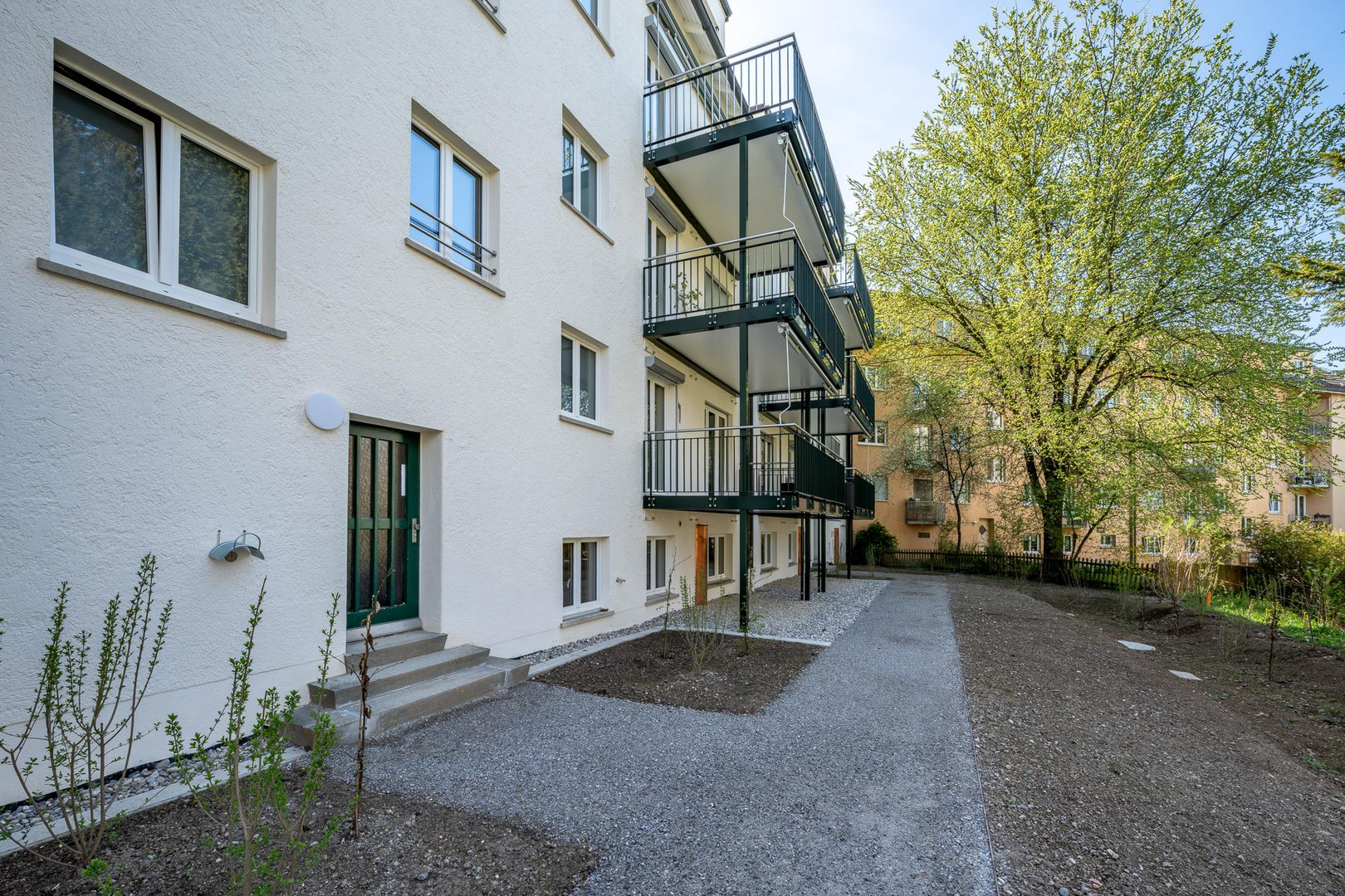 Mehrfamilienhaus mit Balkonen und Gartenansicht