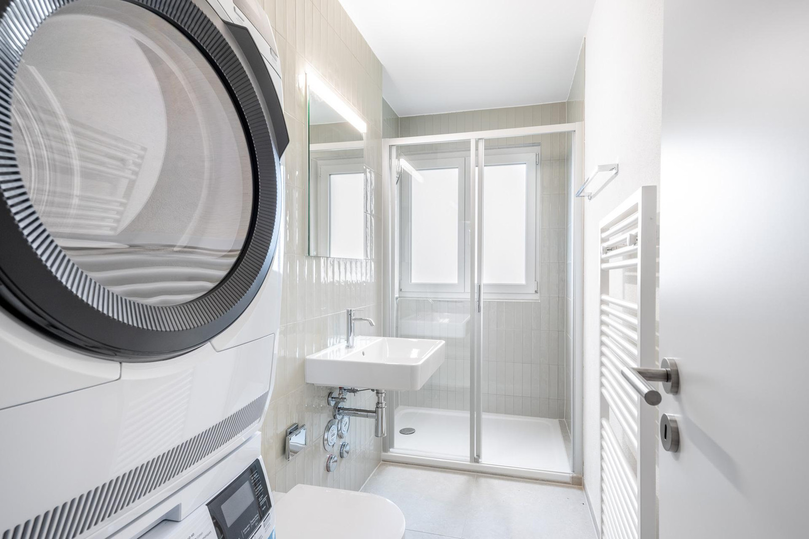 Helles, schmales Badezimmer mit Waschtrockner und Dusche