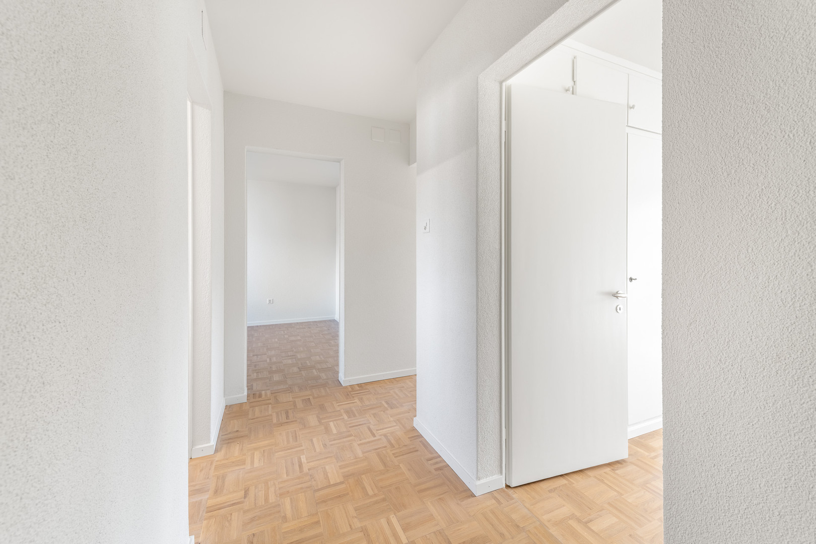 Heller Flur mit Parkett und weißen Türen