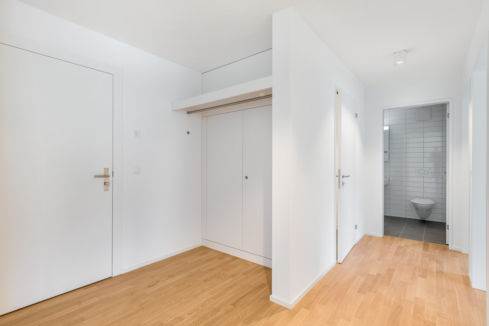 Heller Flur mit Einbauschrank und Blick ins Gäste-WC
