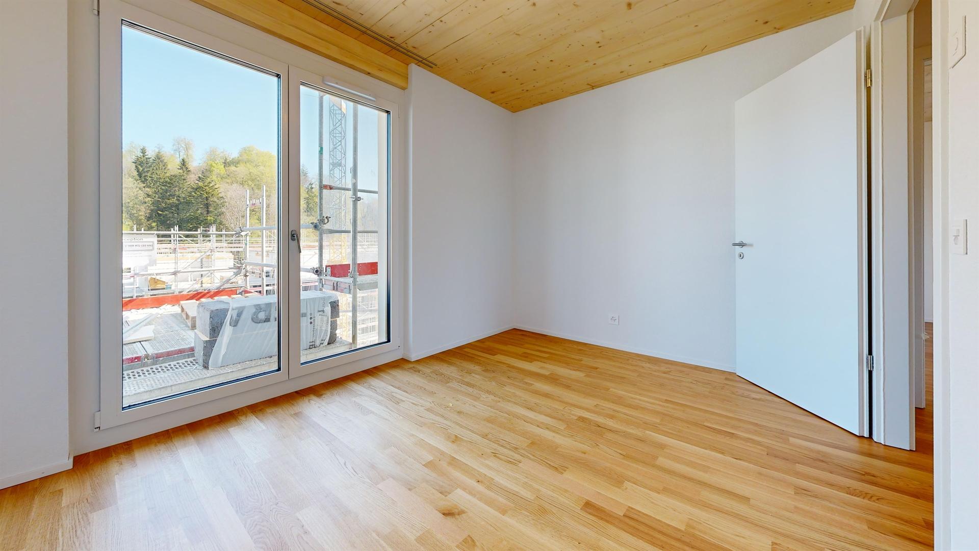 Heller leerer Raum mit Holzdecke und großem Fenster