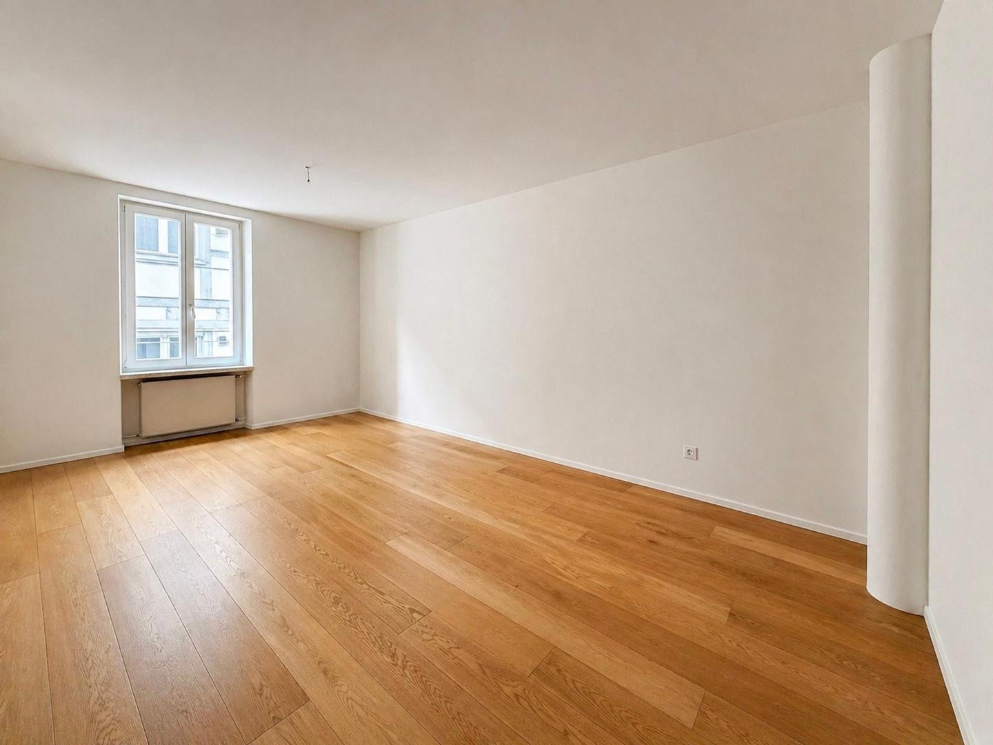 Leerer, heller Wohnraum mit Parkettboden