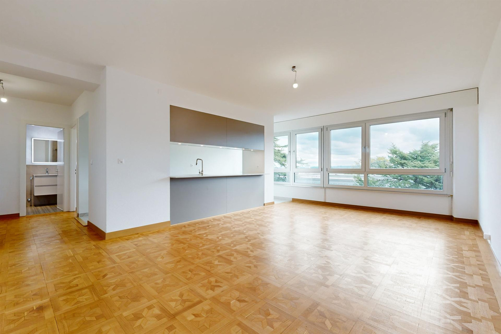 Helles Wohnzimmer mit offener Küchenzeile und großem Fensterband