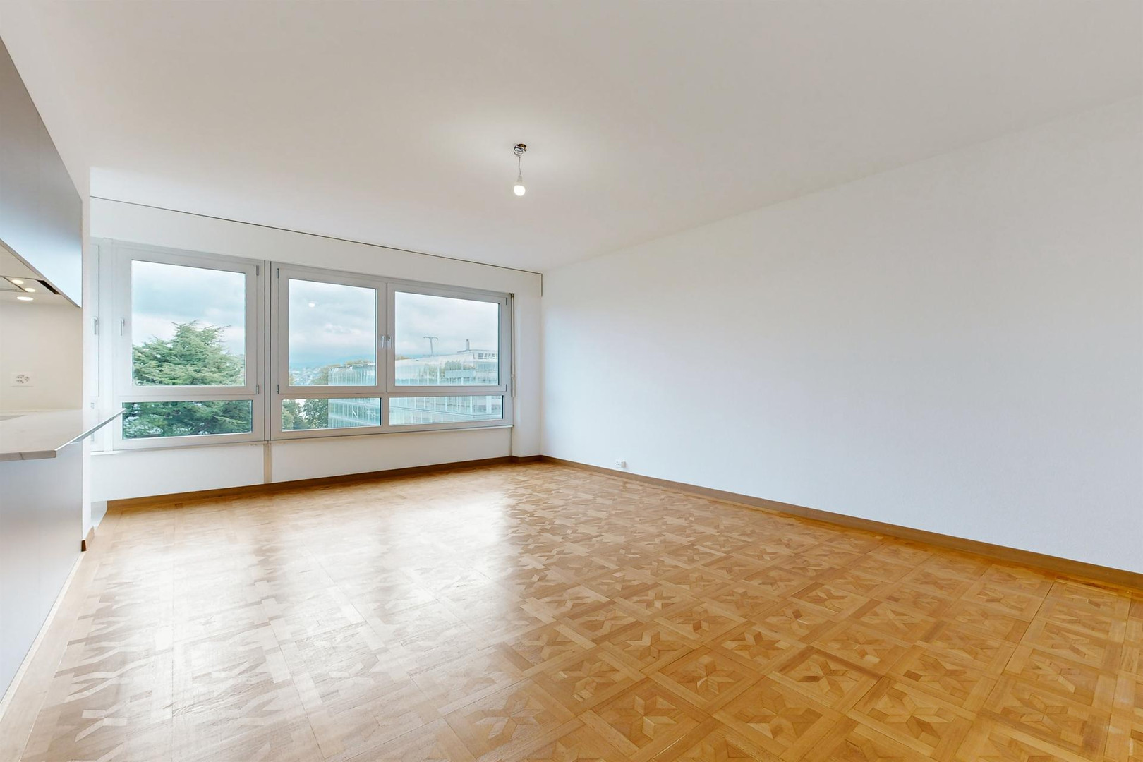 Helles, leeres Wohnzimmer mit großen Fenstern
