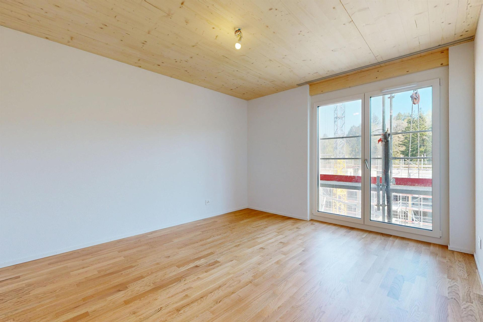 Heller leerer Raum mit Holzdecke und Balkontür