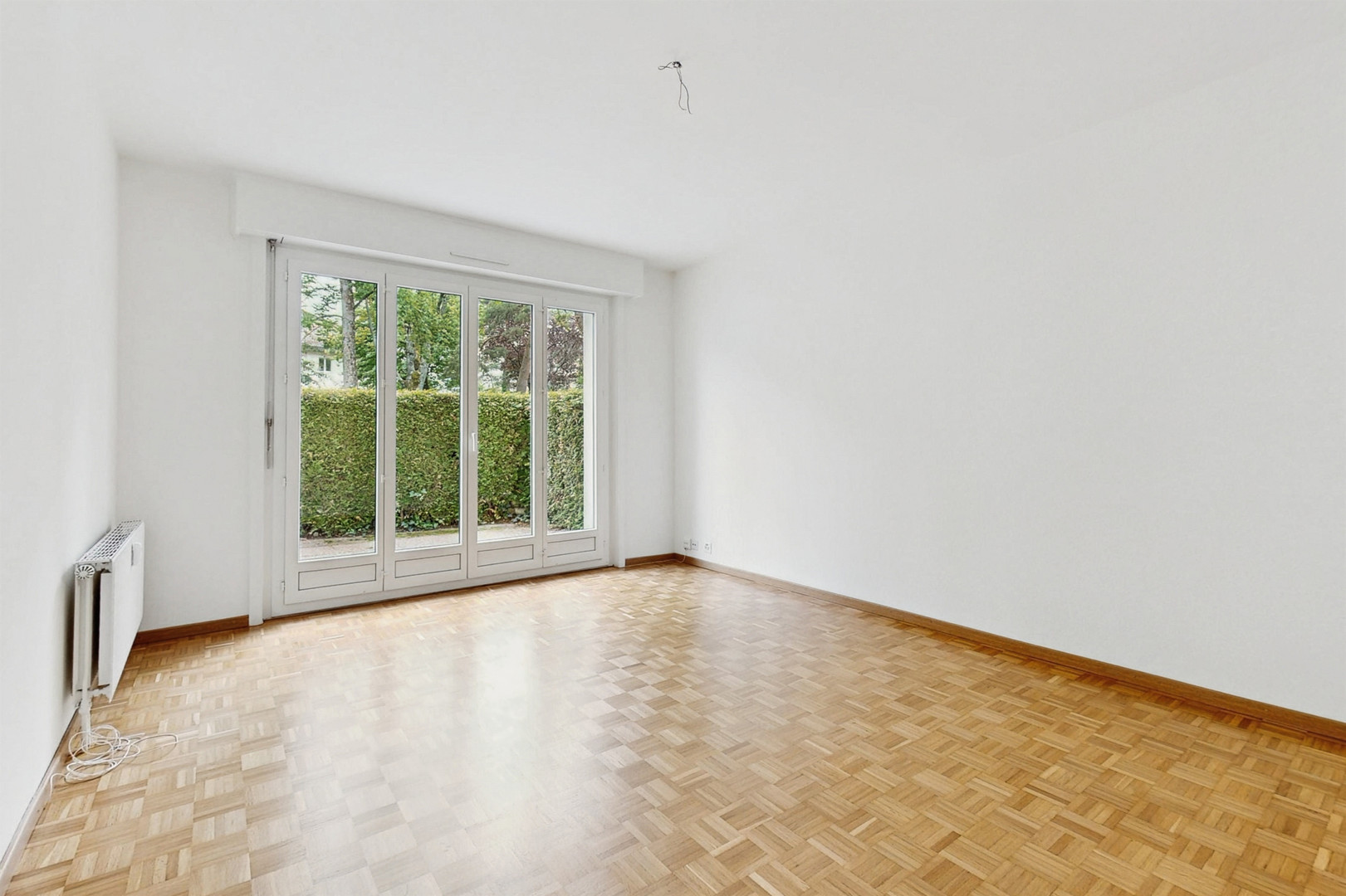Leerer Wohnraum mit Parkett und Balkon-/Terrassentür