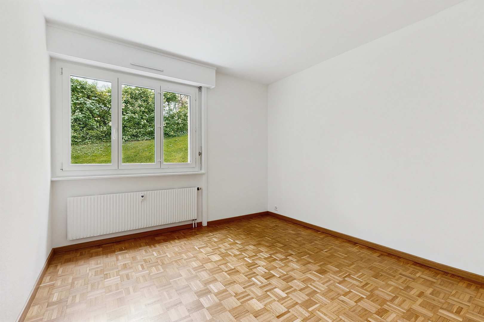 Leerer heller Raum mit Fenster und Parkettboden
