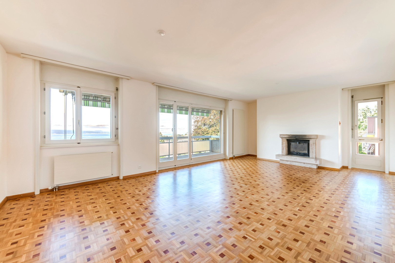 Heller leerer Wohnraum mit Kamin und Meerblick