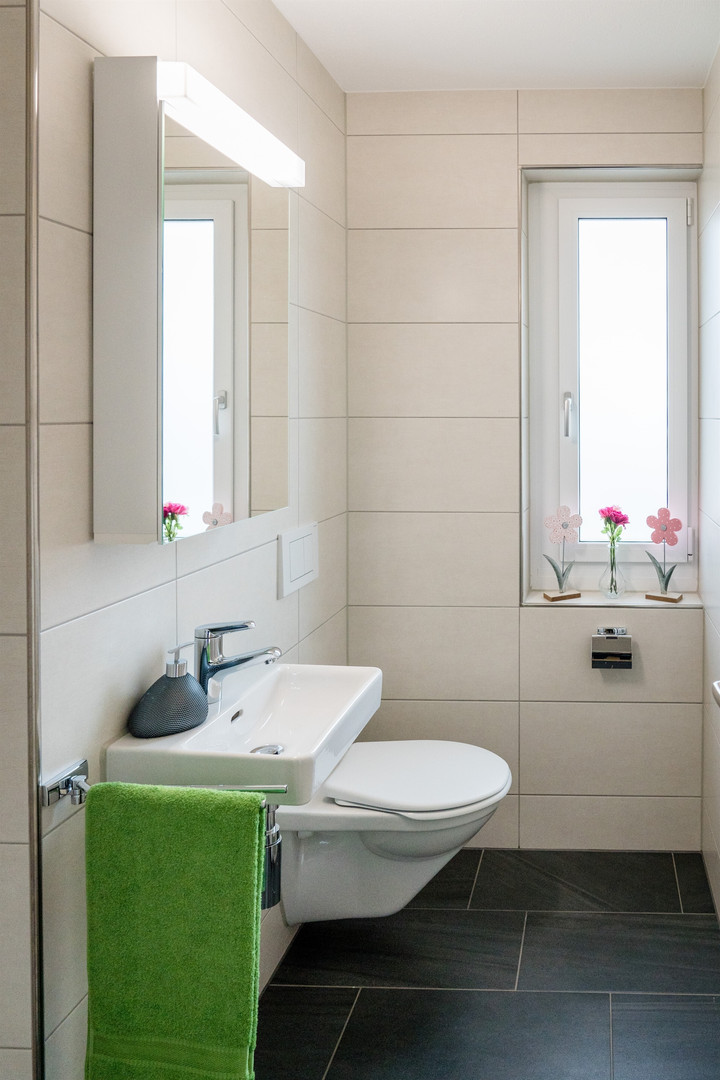Gäste-WC mit schmalem Fenster und Wand-WC