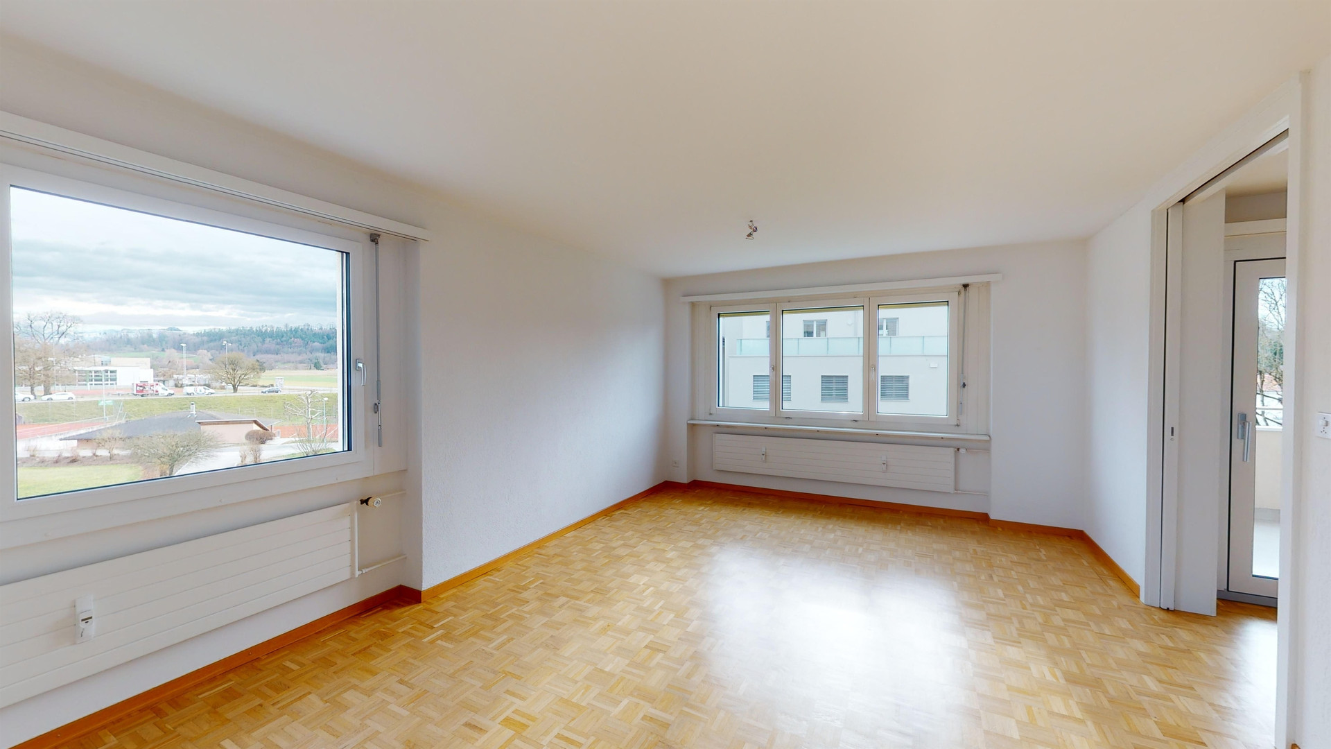 Helles, leerstehendes Wohn-/Schlafzimmer mit Parkett und großen Fenstern