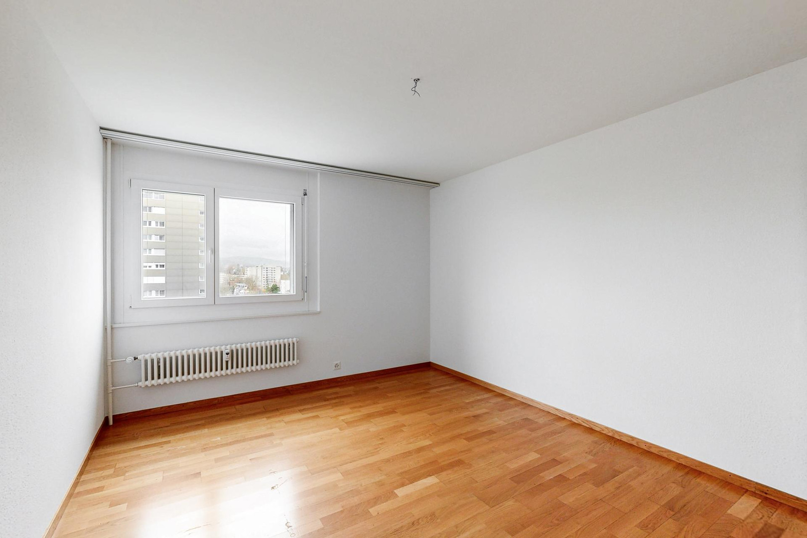 Heller, leerer Wohnraum mit Fenster und Heizkörper