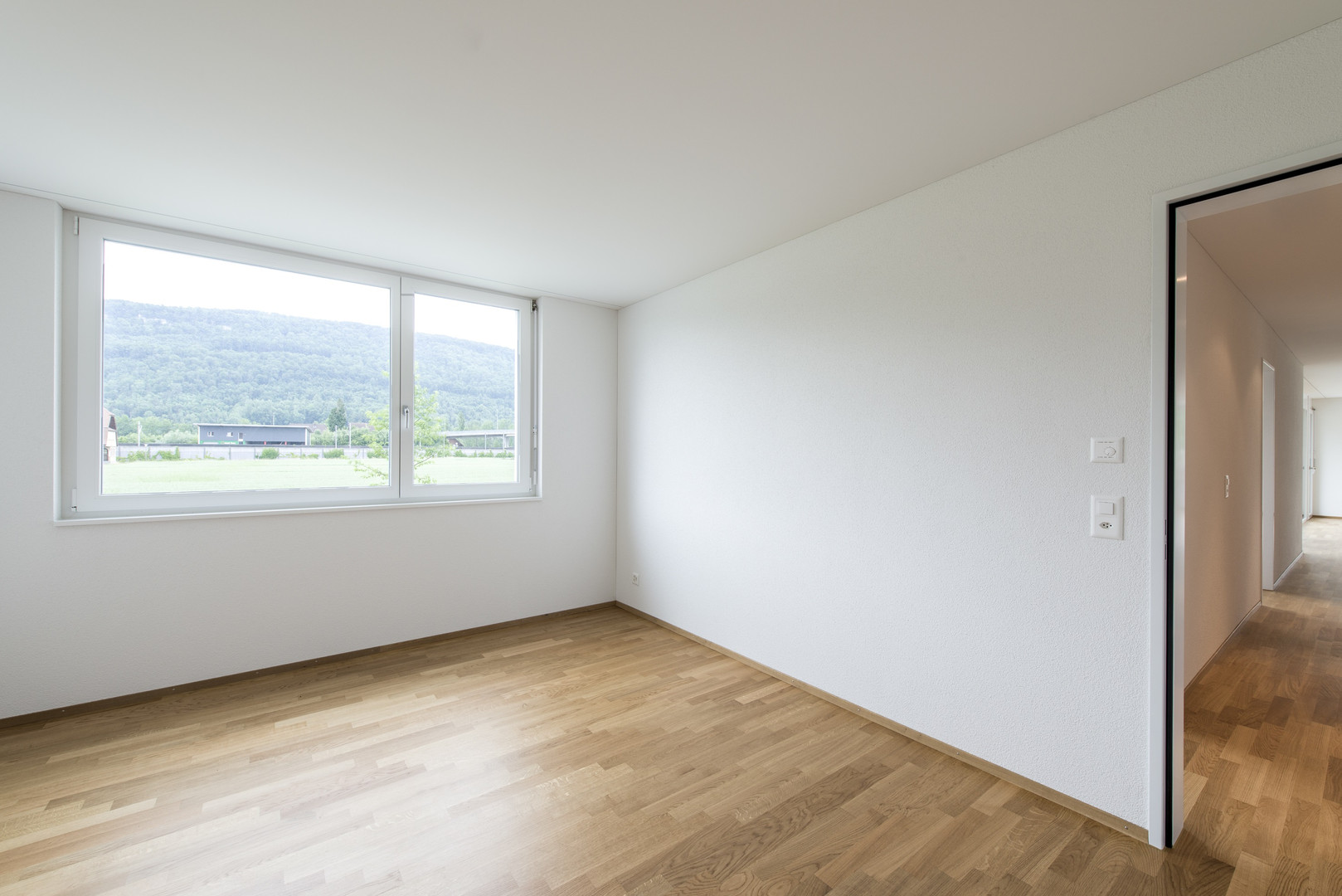 Helles leeres Zimmer mit Holzfußboden