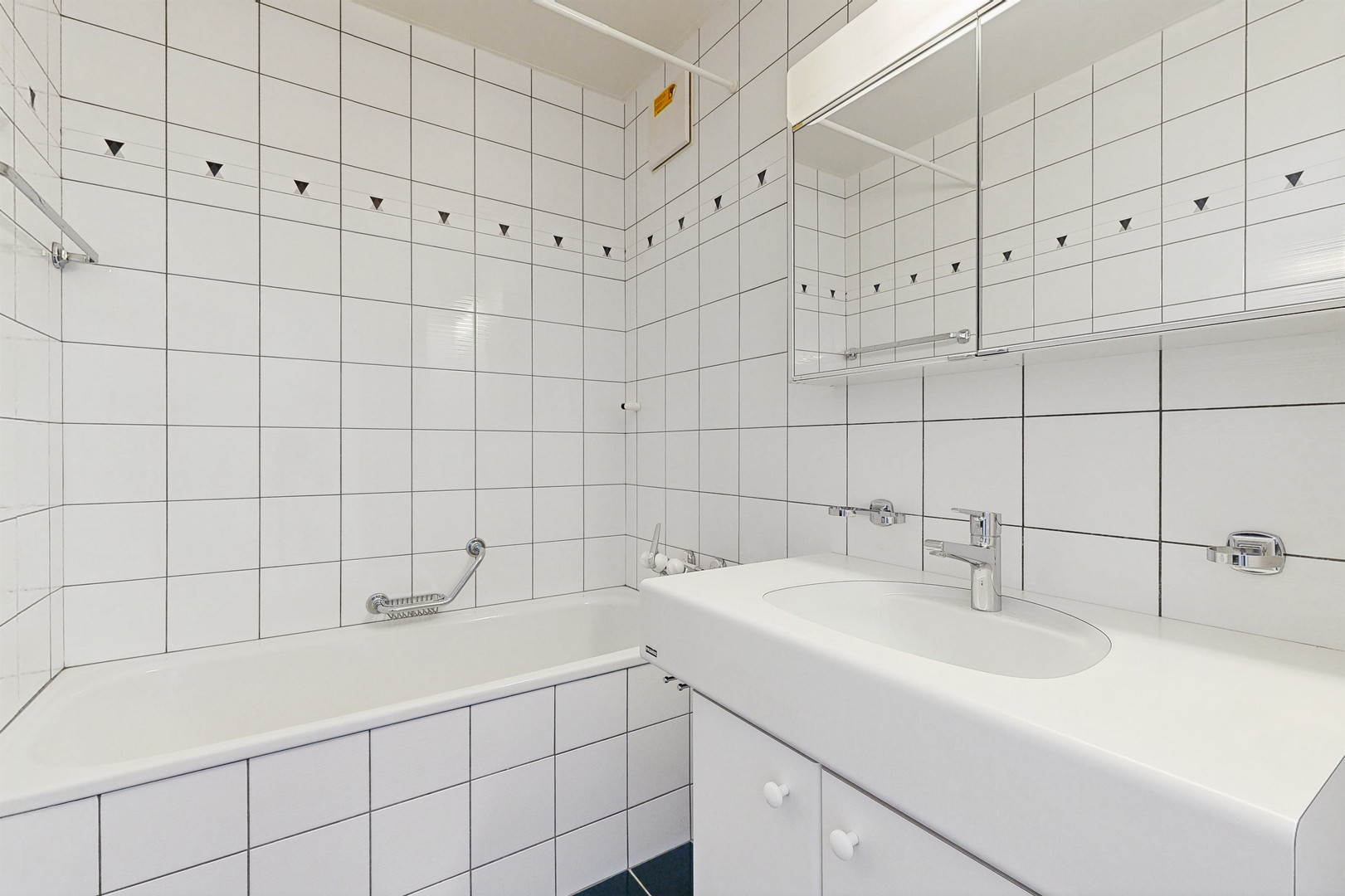 Badezimmer mit weiß gefliesten Wänden und Badewanne