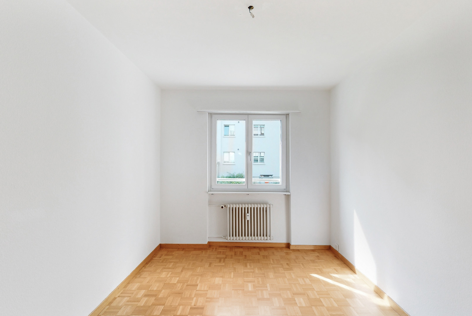 Leerer heller Raum mit Fenster und Heizkörper