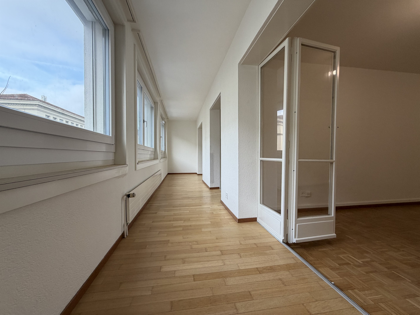 Heller Flur mit Parkett und großen Fenstern