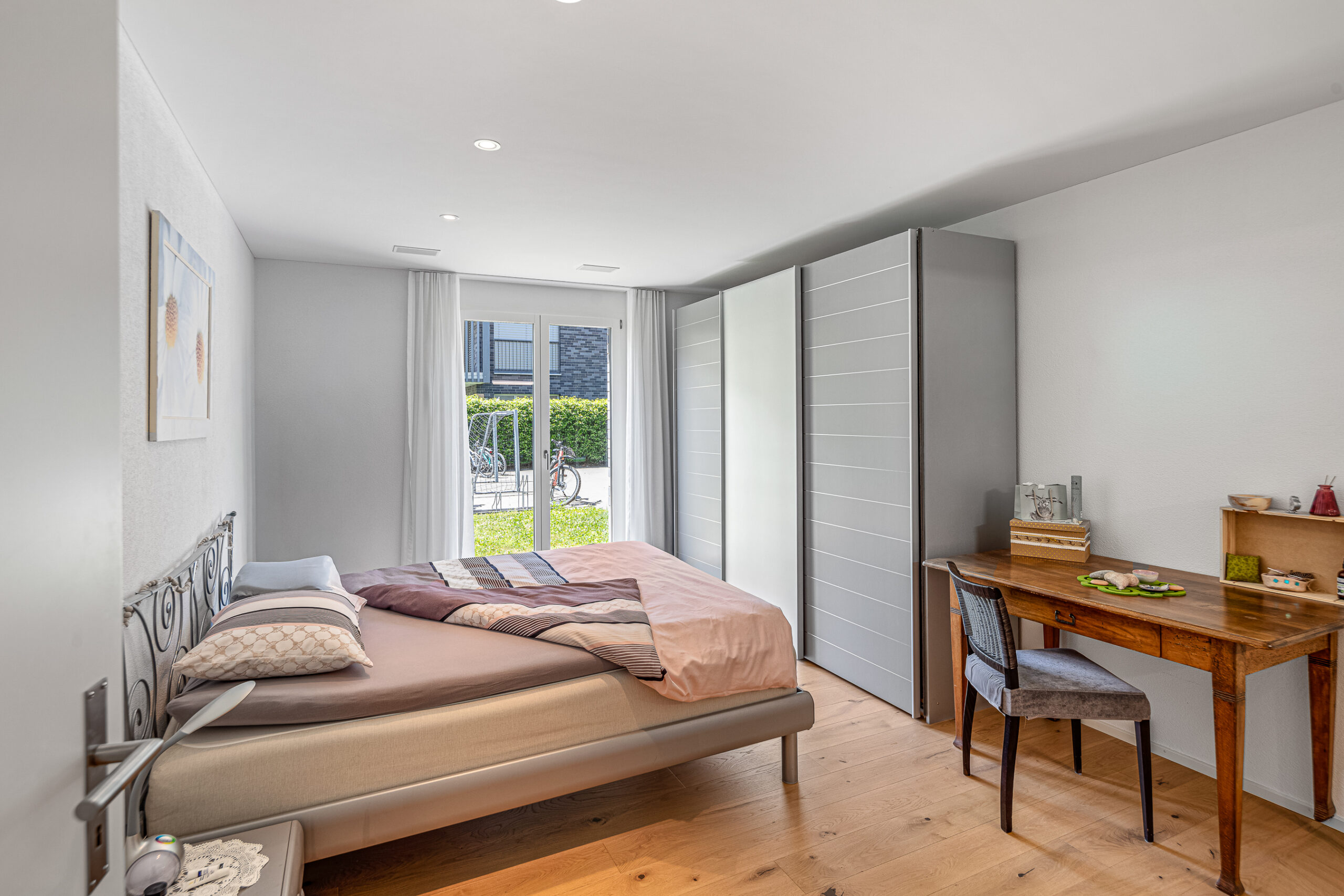 Helles Schlafzimmer mit Bett, Schreibtisch und Kleiderschrank