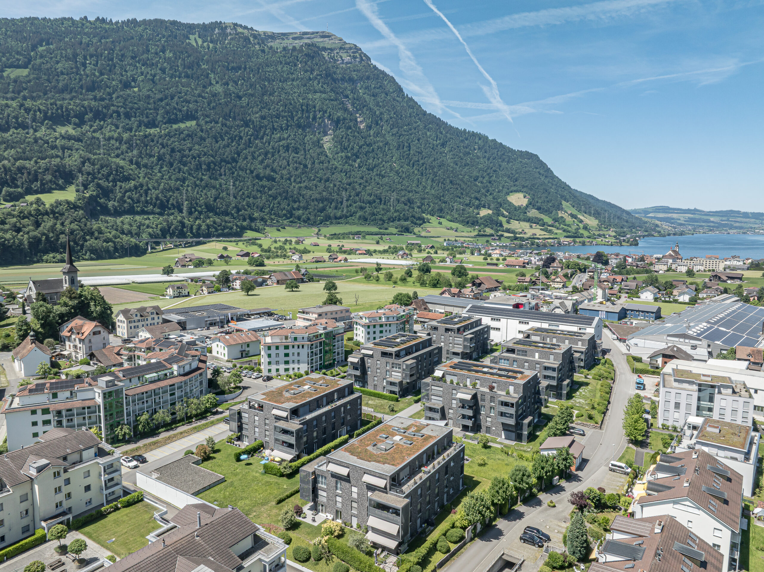 Luftaufnahme einer Berg- und Seenlandschaft mit Wohnsiedlung