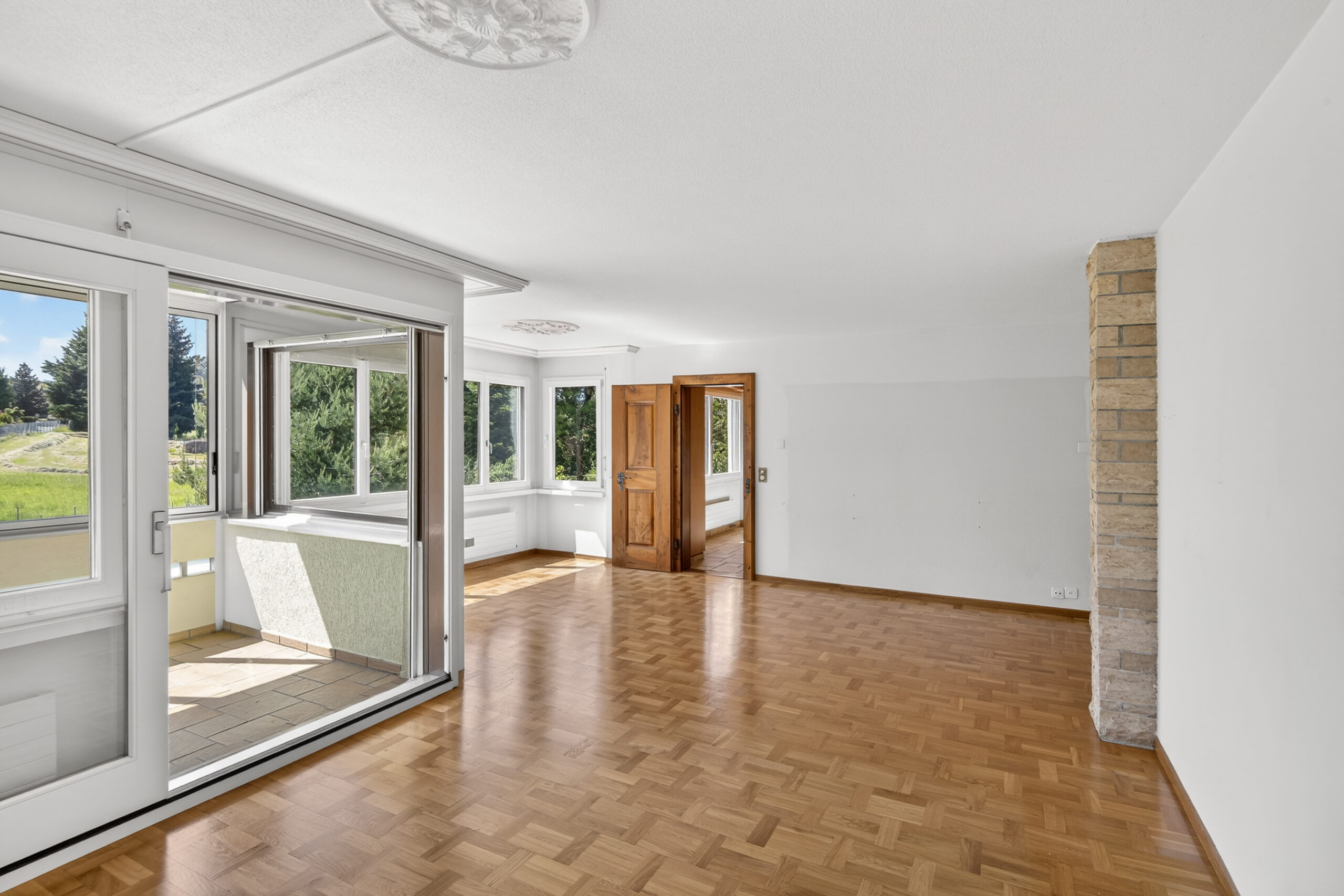 Heller leerer Wohnraum mit Zugang zum verglasten Balkon