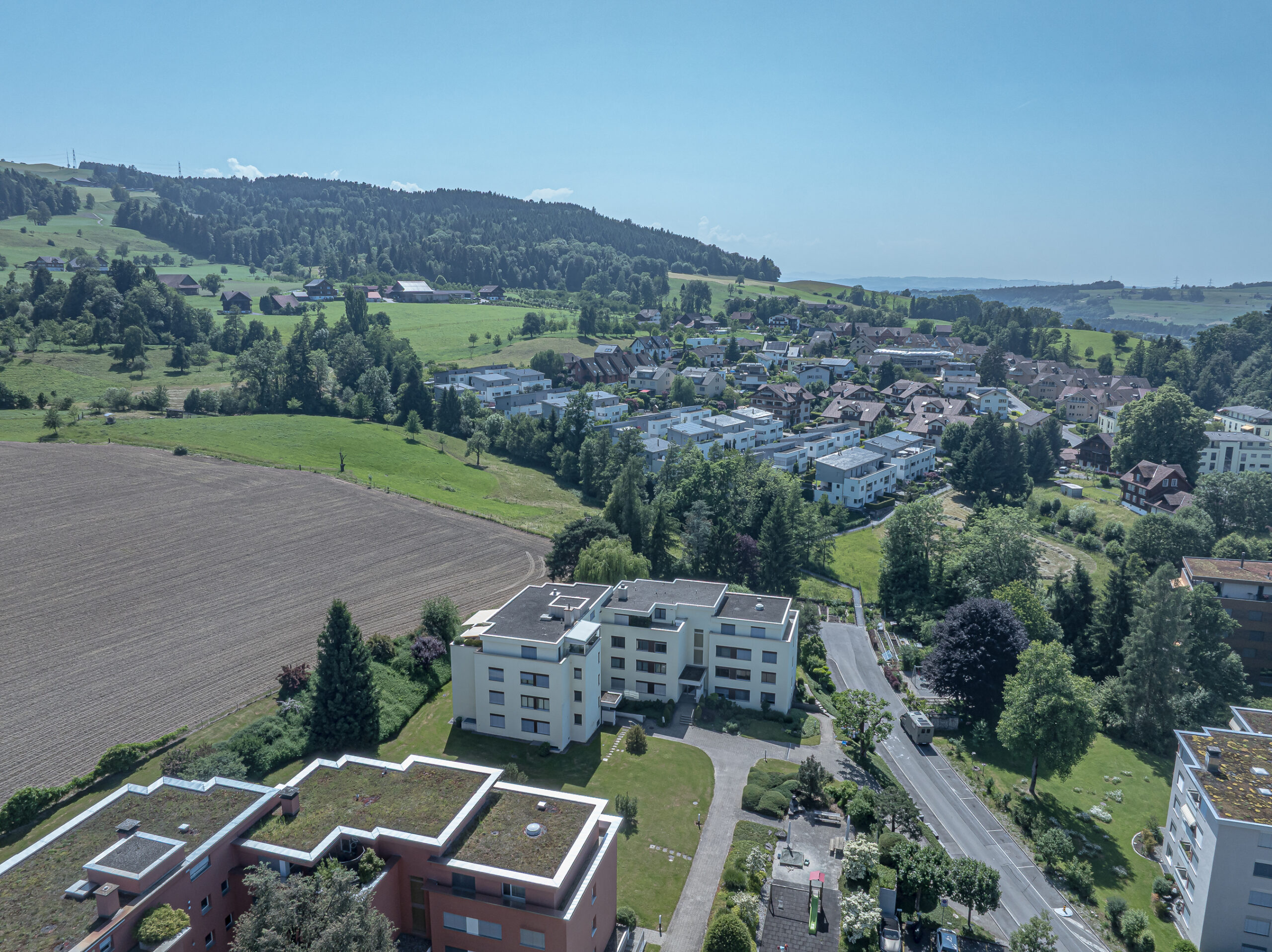 Luftaufnahme eines grünen Wohngebiets mit Dorf- und Landschaftsblick