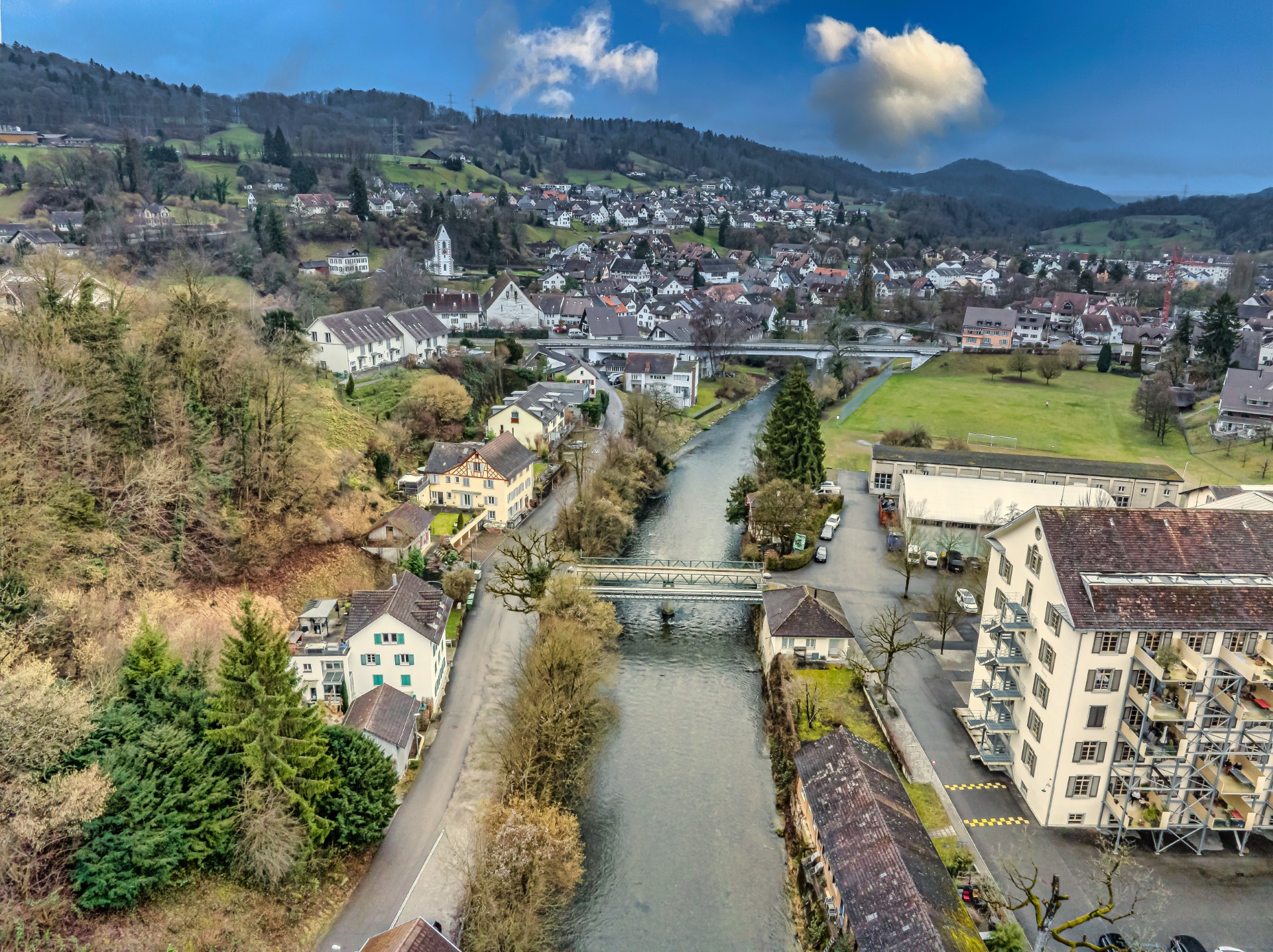 Luftaufnahme einer Flussstadt mit Brücken und grüner Hügellandschaft