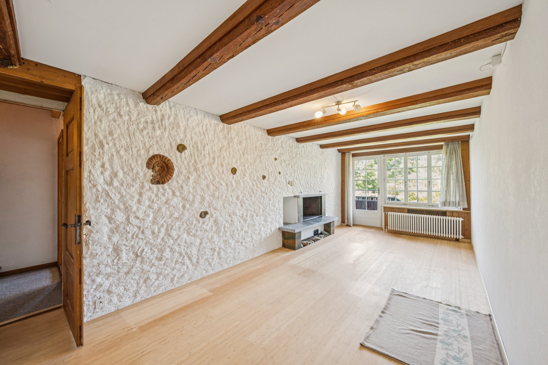 Wohnzimmer mit sichtbaren Holzbalken und Kaminecke