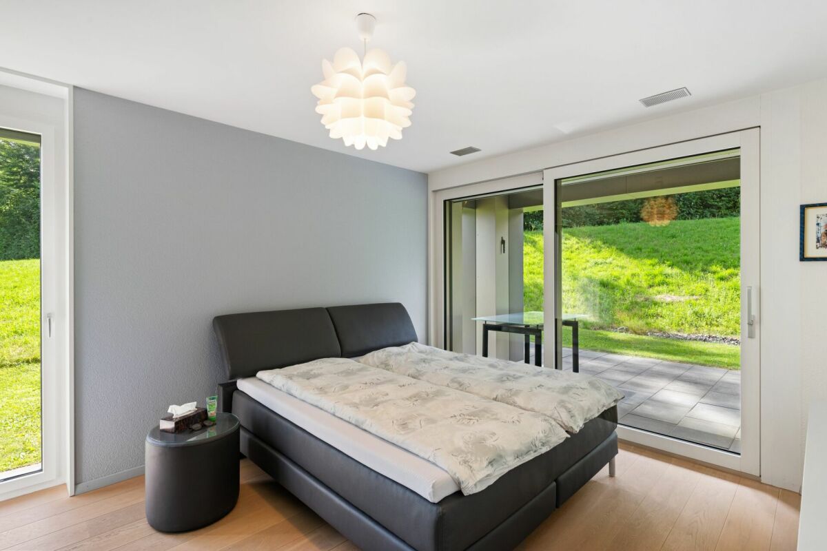 Modernes Schlafzimmer mit großem Schiebetürfenster zum Garten