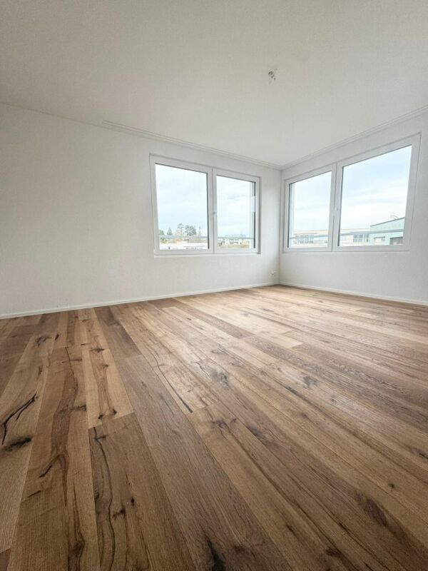Leerer heller Raum mit Holzboden und Eckfenstern