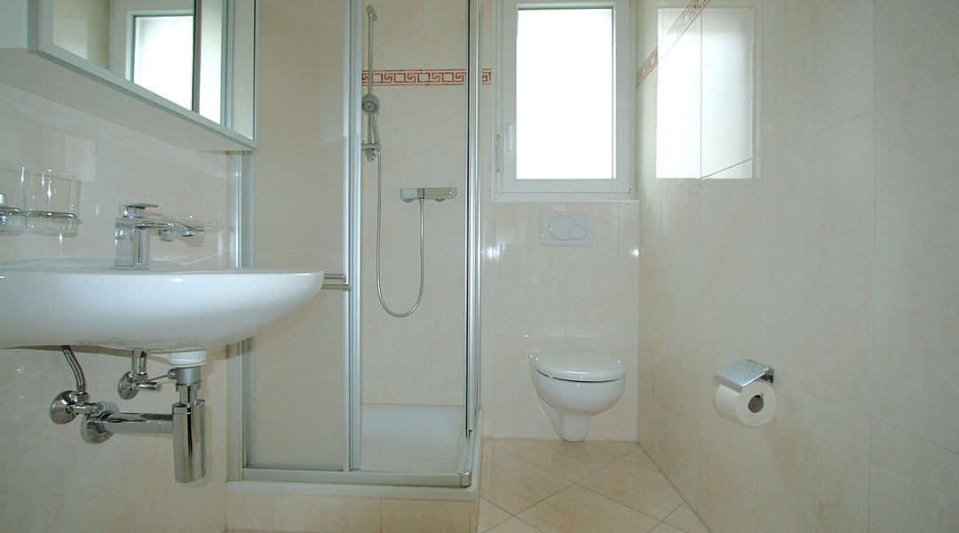 Hell gefliestes Badezimmer mit Dusche und WC