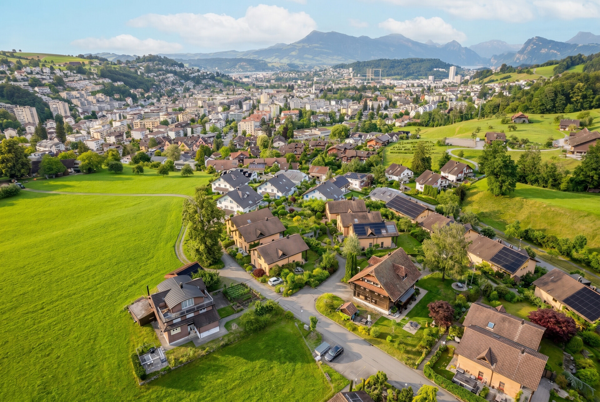 Luftaufnahme eines grünen Wohnviertels mit Bergpanorama