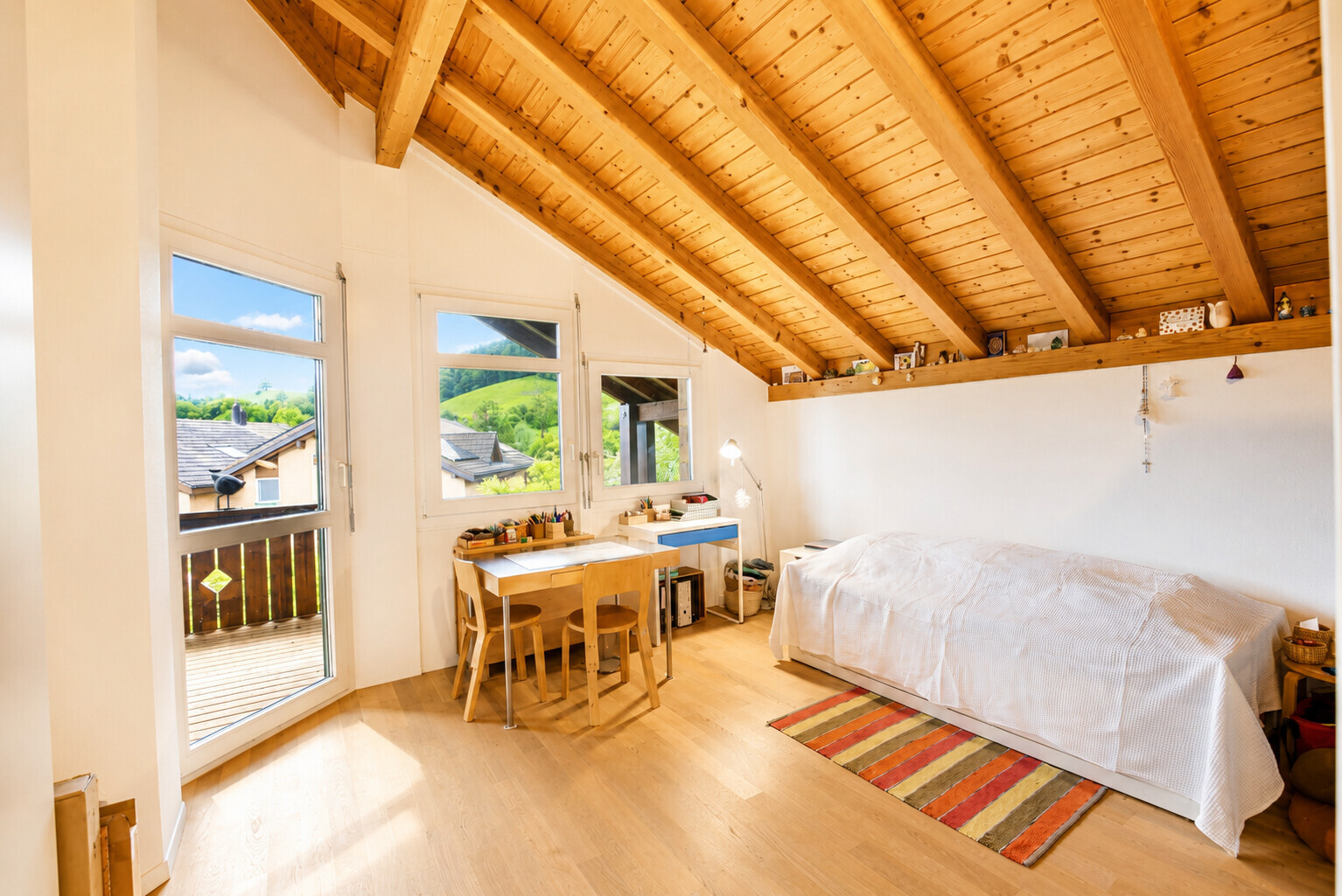 Heller Dachraum mit Holzsichtdecke und Bett
