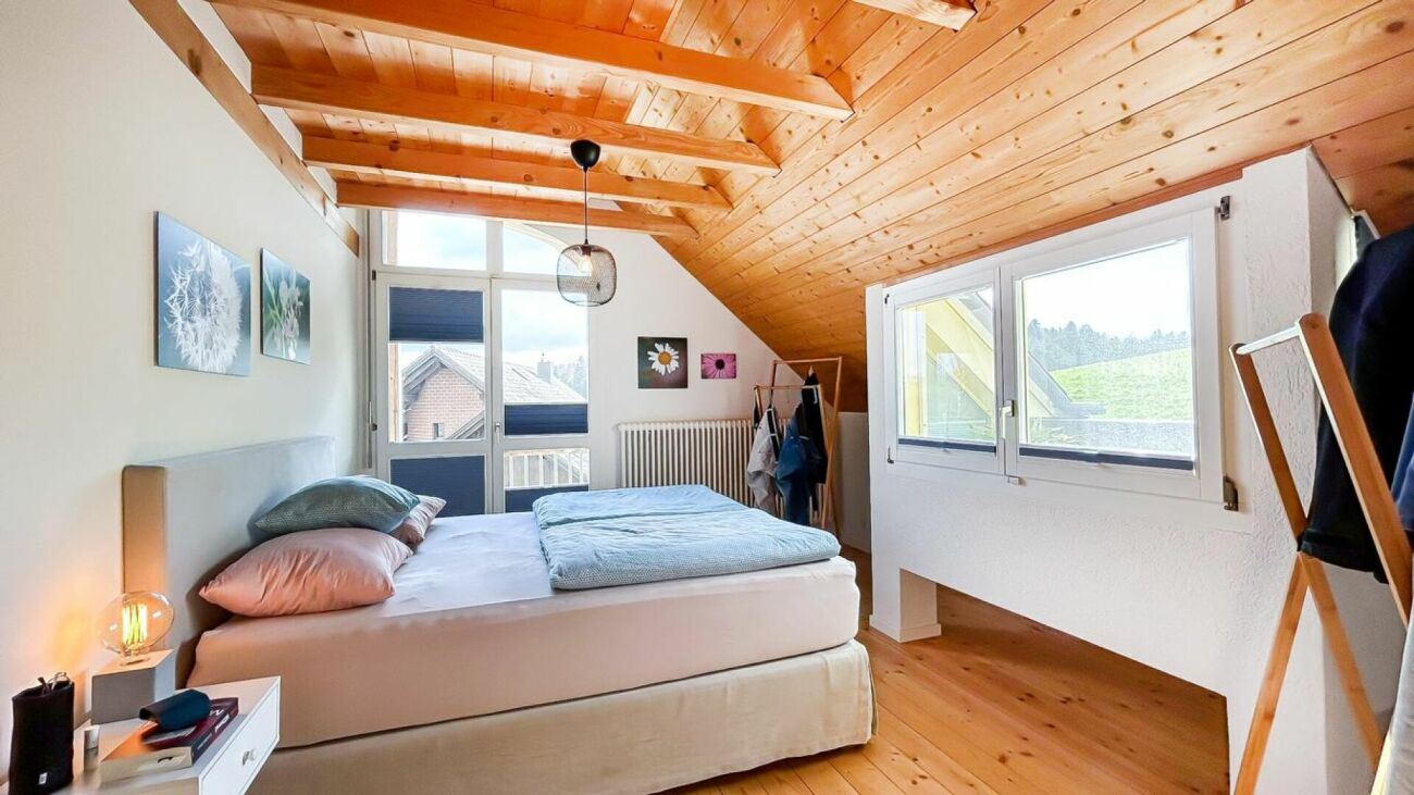 Gemütliches Schlafzimmer mit Holzdecke und Balkonblick