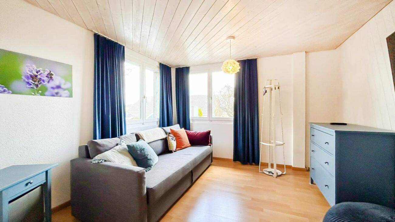Gemütliches Wohnzimmer mit Sofa und blauem Vorhang