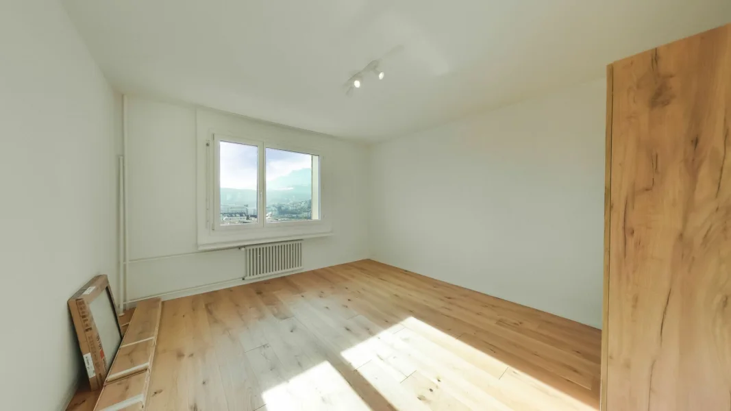 Heller leerer Raum mit Holzboden und Fensterblick