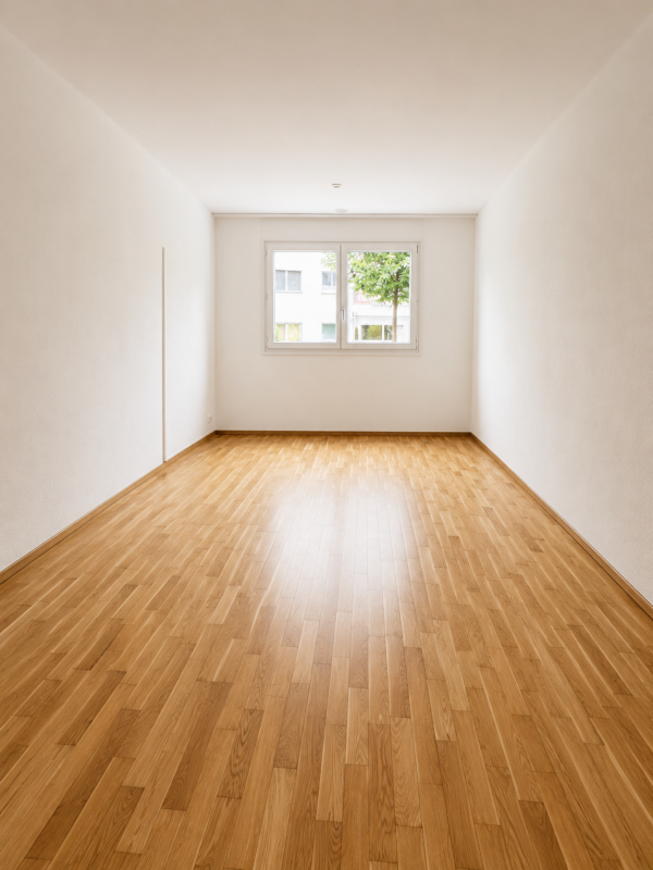 Leerer heller Wohnraum mit Parkett und Fenster