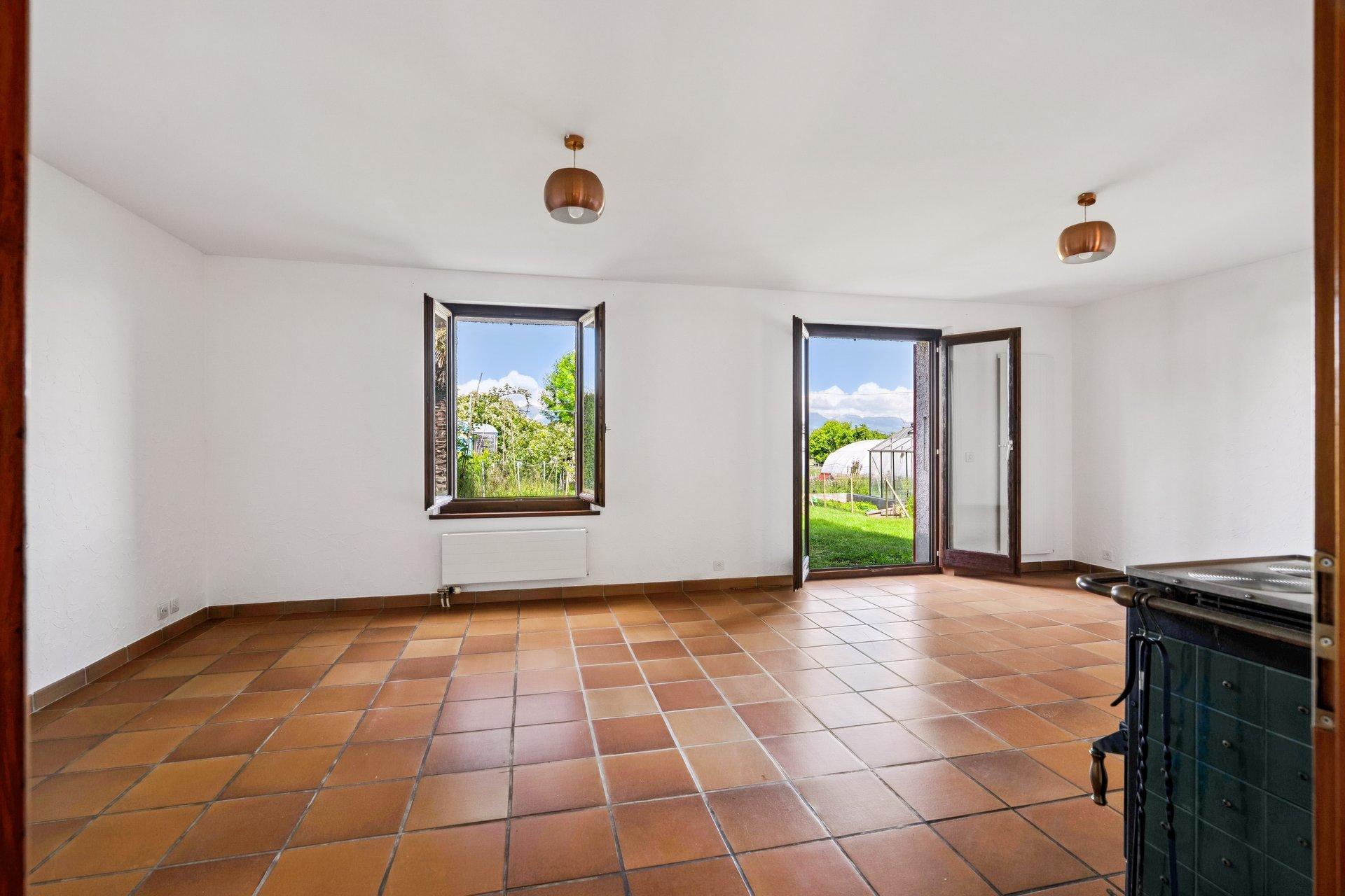 Heller leerer Wohnraum mit Terrakottafliesen und Gartenzugang