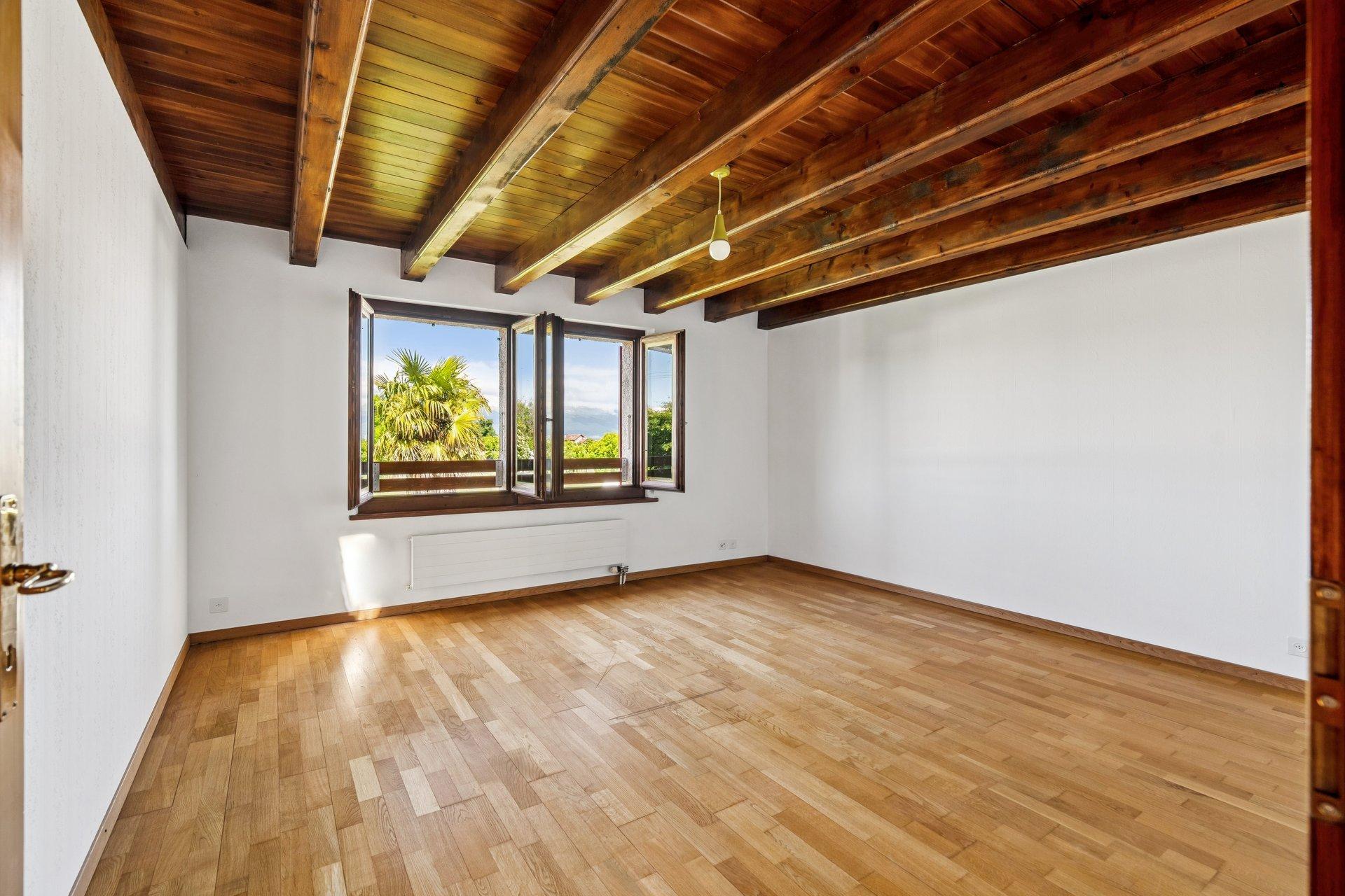 Leeres Zimmer mit Holzbalkendecke und Blick ins Grüne