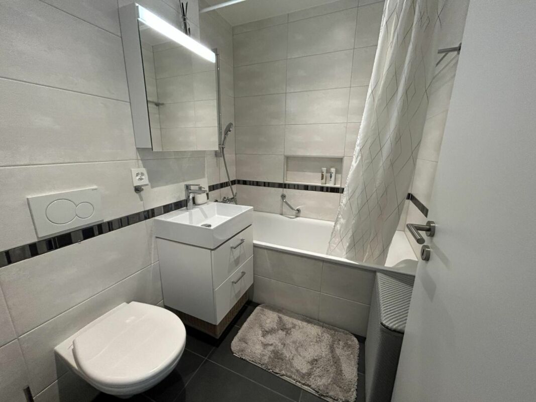 Kleines, modernes Badezimmer mit Badewanne und Wand-WC