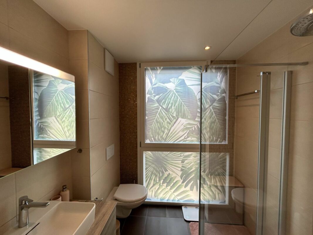Modernes Badezimmer mit Duschkabine und Fensterfolierung