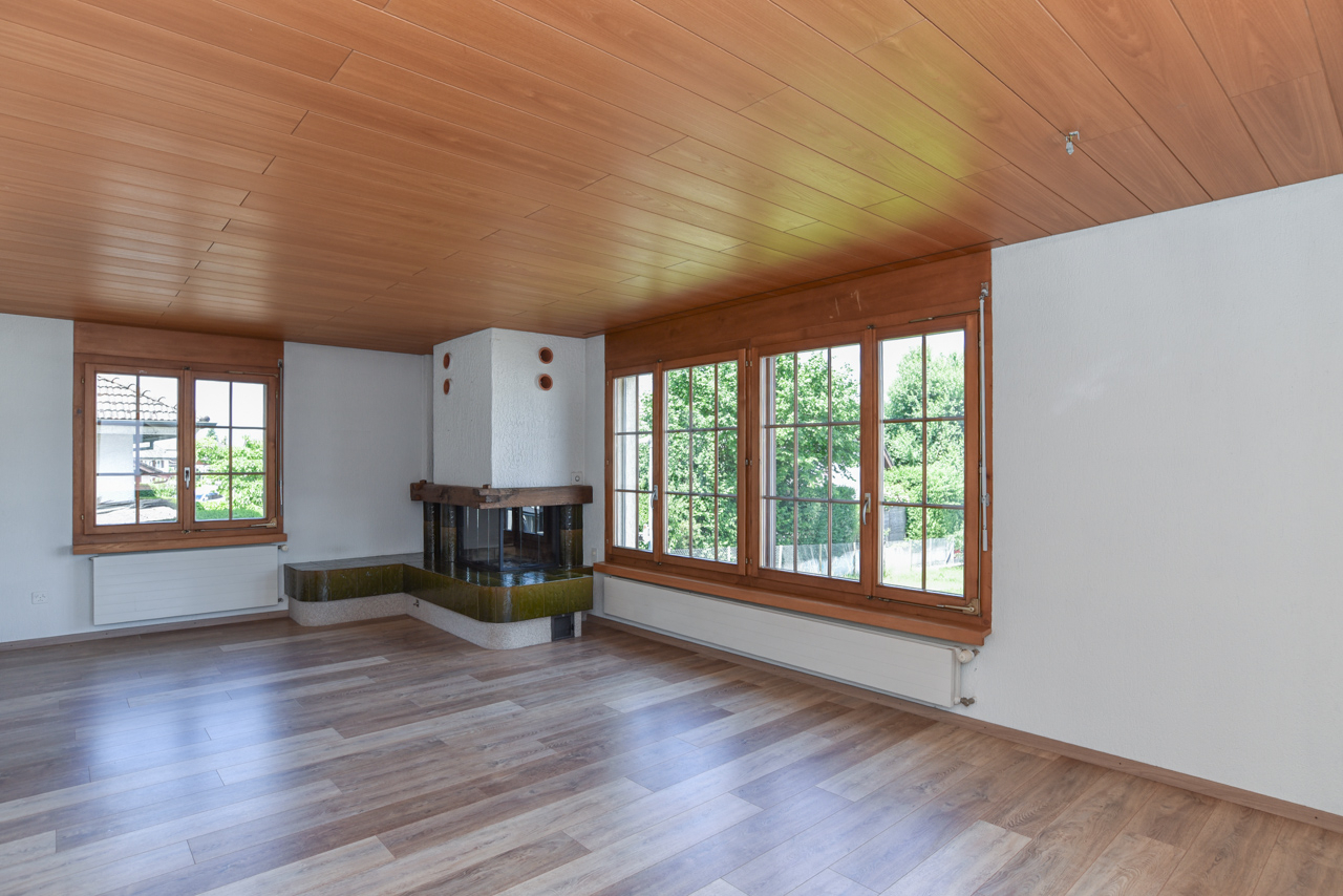 Wohnzimmer mit Kamin und großen Holzfenstern
