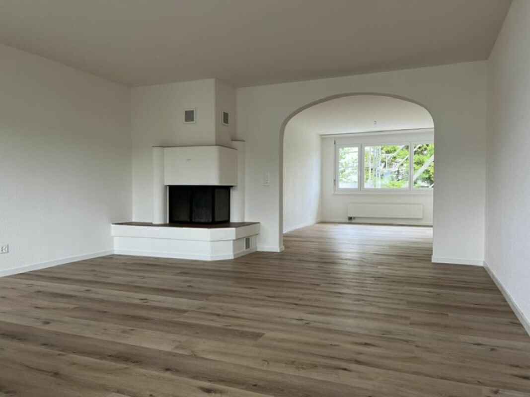 Heller Wohnraum mit Kamin und Durchgang zum Nebenraum
