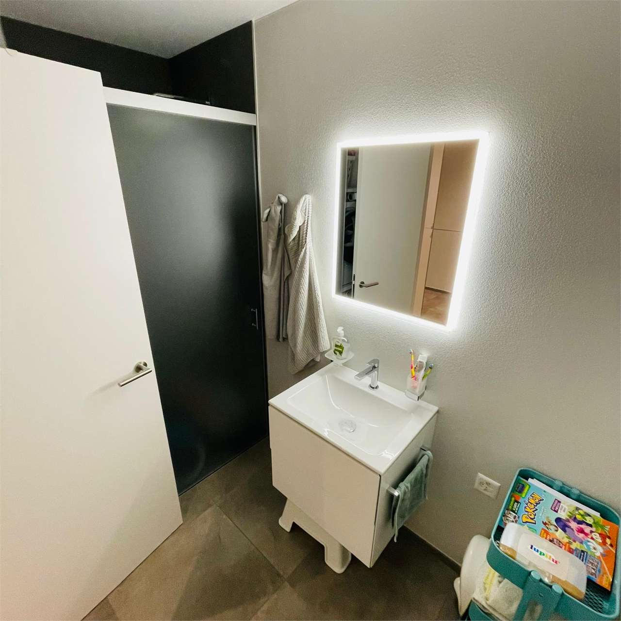 Modernes Badezimmer mit beleuchtetem Spiegel und Waschtisch