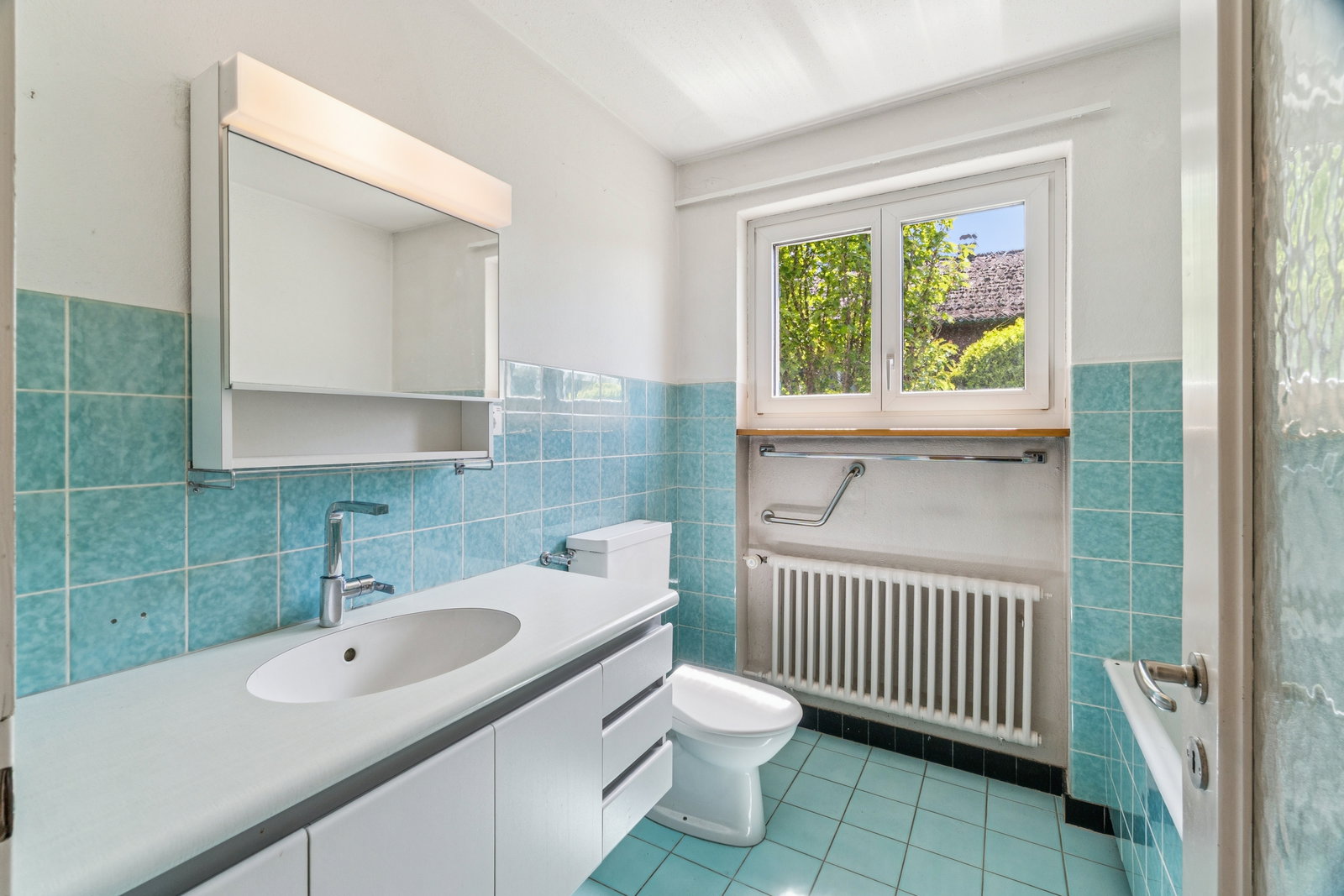 Badezimmer mit türkisfarbenen Fliesen und Fenster