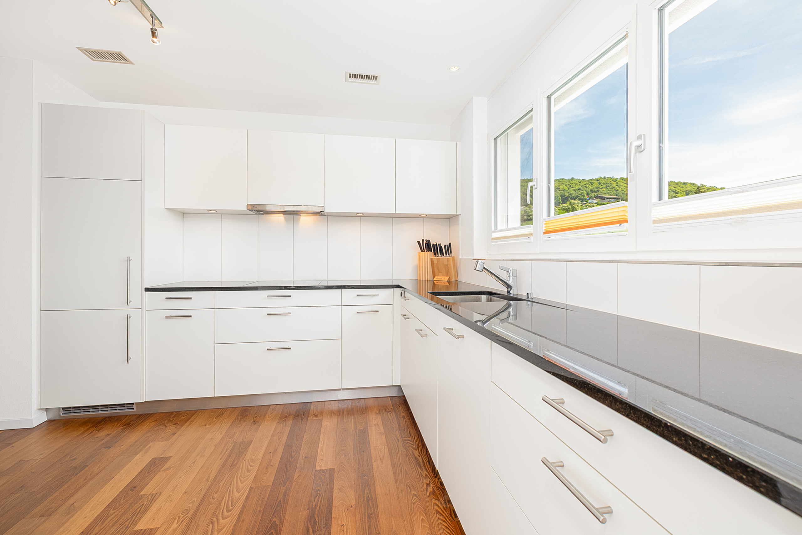 Moderne weiße Küche mit Holzfußboden