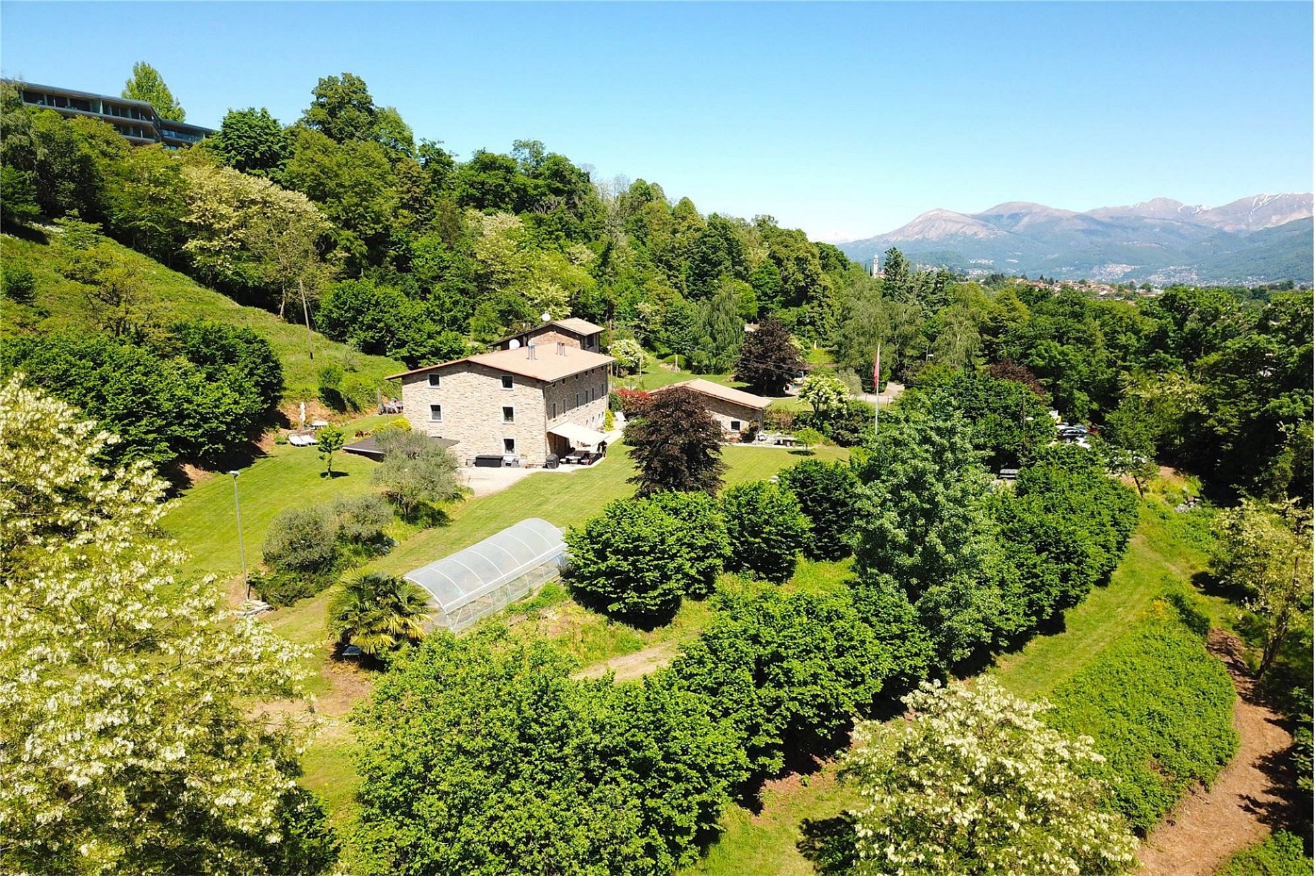 Luftaufnahme eines ländlichen Anwesens mit Garten und Bergblick