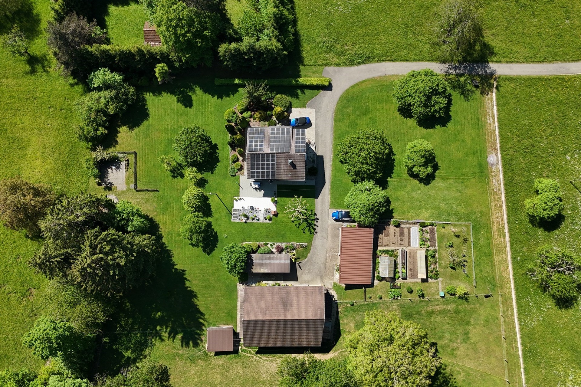 Luftaufnahme eines ländlichen Anwesens mit Haus, Nebengebäuden und Solaranlage
