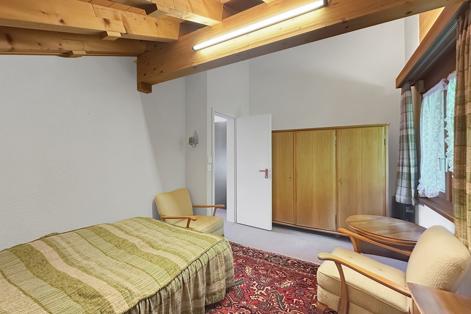 Rustik eingerichtetes Schlafzimmer mit Holzbalkendecke